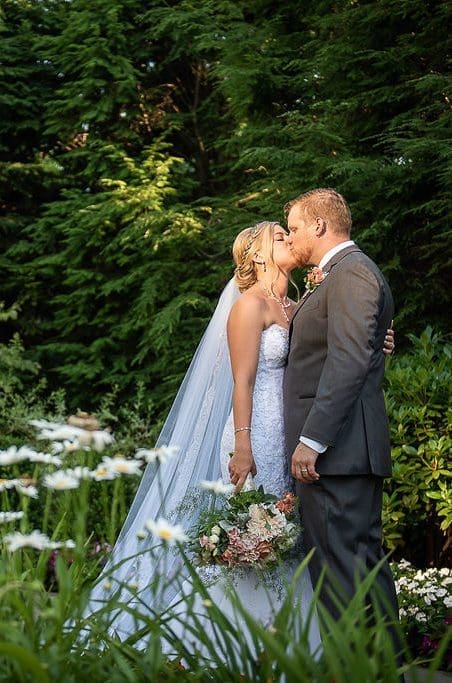 bride and groom kissing by a water fountain