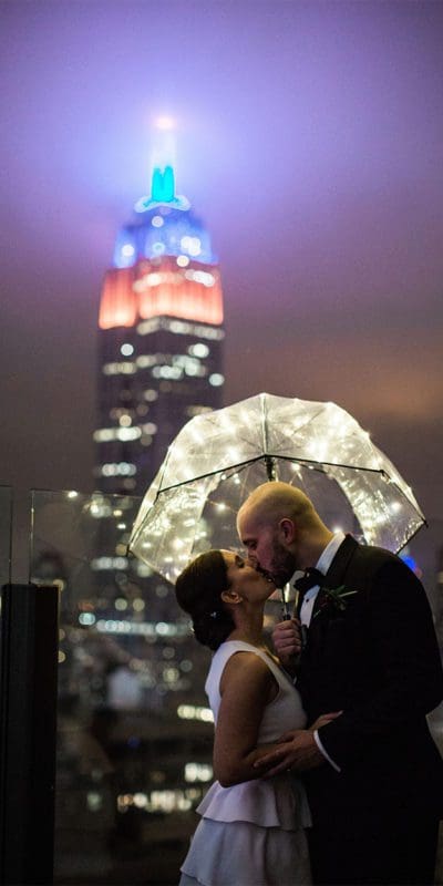 bride and groom embracing outside under umbrella