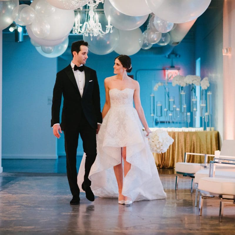 bride and groom holding hands walking down hallway
