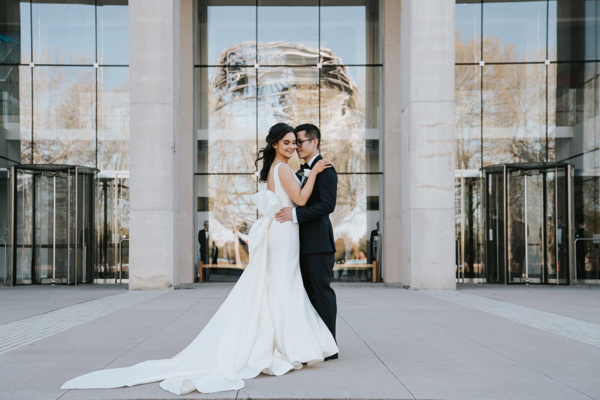 bride and groom embracing outside of the queens museum entrance