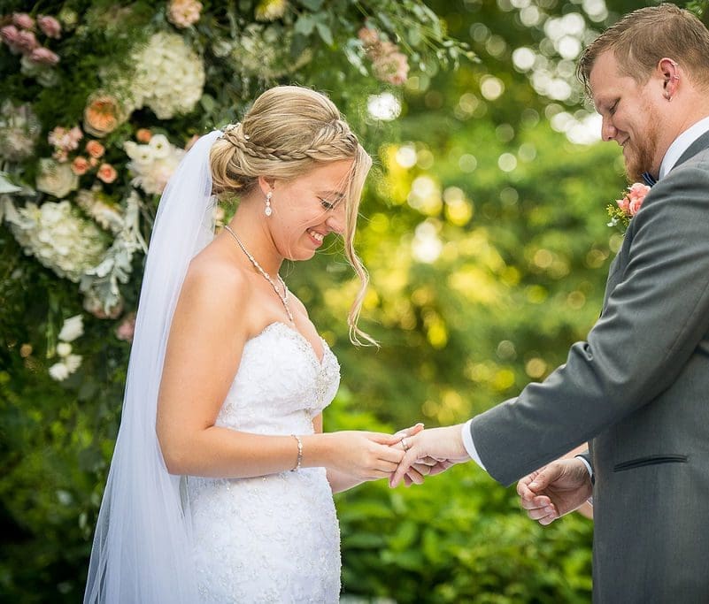 bride putting a ring on a grooms hand