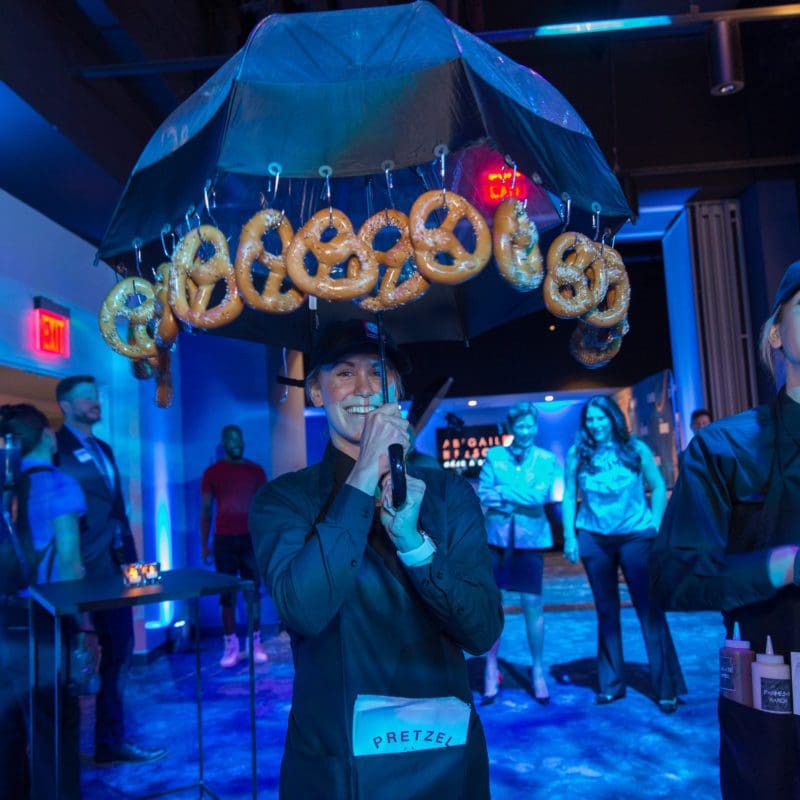 waiter holding an umbrella with pretzels hanging from the sides