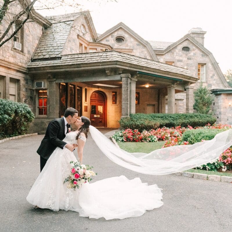 bride and groom kissing in front of mansion