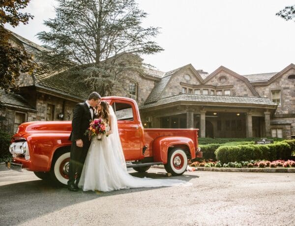 bride and groom embracing in front of antique car