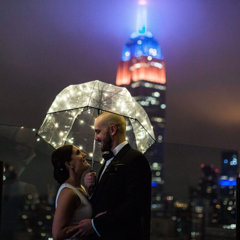 bride and groom embracing under an umbrella outside