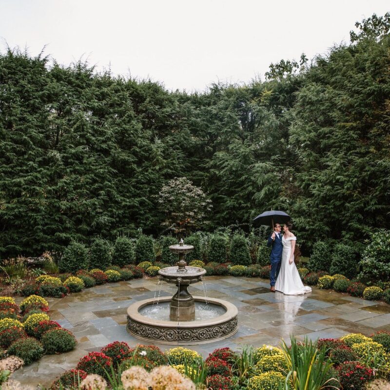 bride and groom embracing in front of water fountain