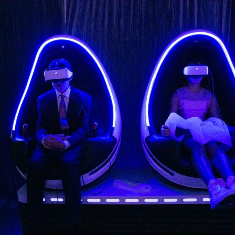 two people sitting in egg chairs wearing VR sets