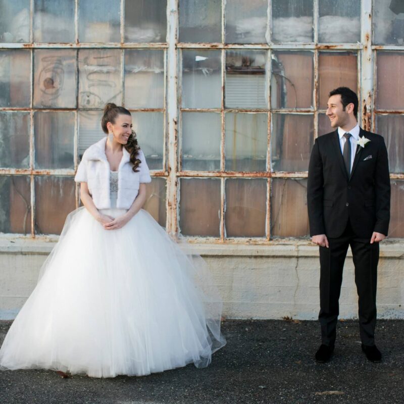 bride and groom smiling and looking at each other outside