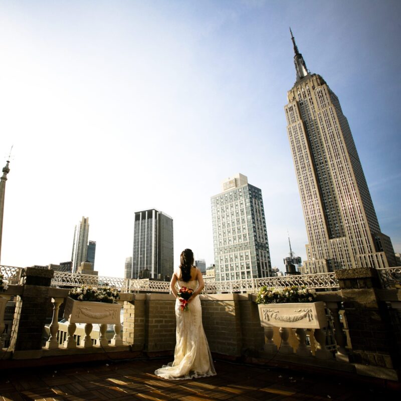 woman in wedding dress standing on a rooftop looking at the new york skyline