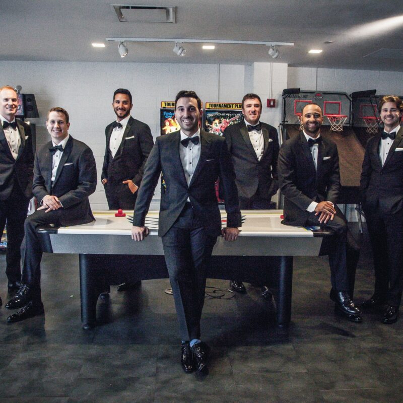 Groomsmen pose in the arcade room.